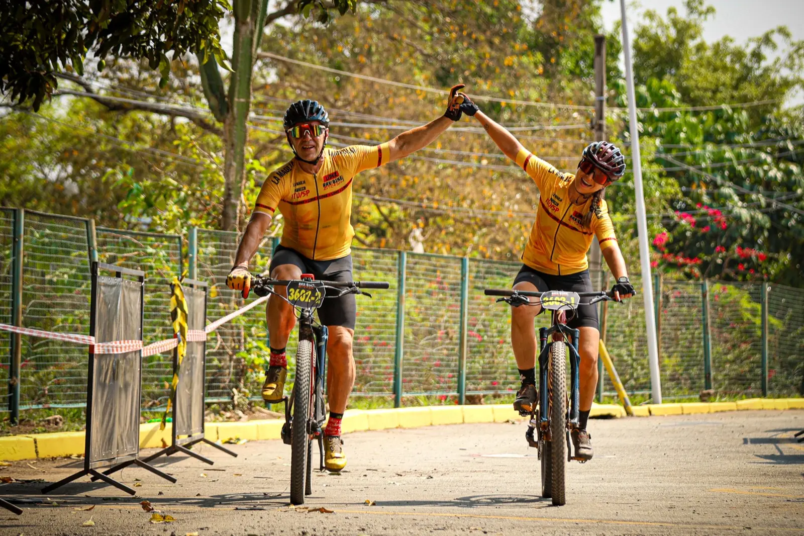 Dupla cruzando a linha de chegada de mãos dadas